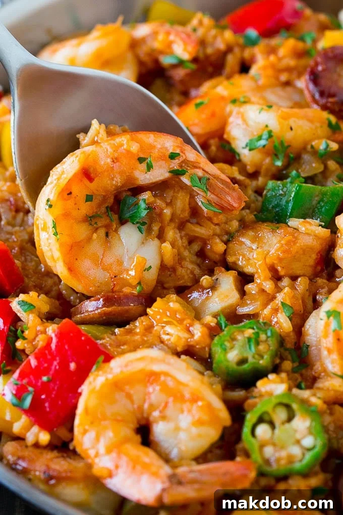 A spoon lifting a serving of rich jambalaya, highlighting succulent shrimp, tender okra, and perfectly cooked rice.