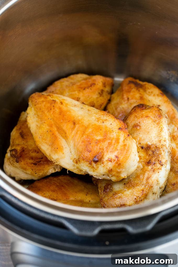 Sauteed chicken breasts browning in an Instant Pot on the 'Saute' setting.