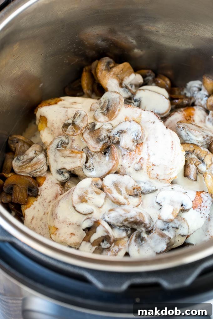 Cooked chicken breasts with a rich, creamy mushroom sauce in an Instant Pot, ready to be served.