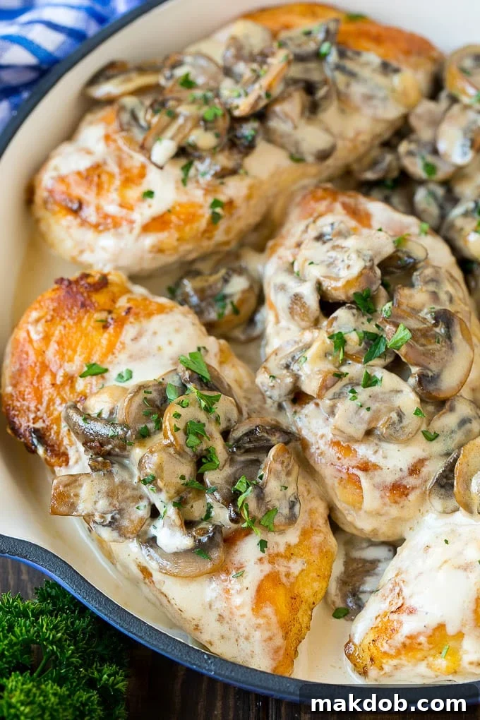 A serving of Instant Pot chicken with creamy mushroom sauce in a pan, garnished with fresh herbs.