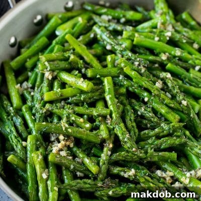 Sauteed asparagus with butter, garlic and herbs in a skillet.