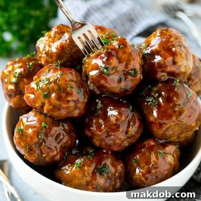 Slow Cooker Sweet and Sour Meatballs 2 A bowl of sweet and sour meatballs with a cocktail fork in it.