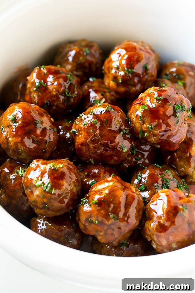 Sweet and Sour Meatballs Recipe | Slow Cooker Meatballs | Crockpot Meatballs | Cocktail Meatballs #meatballs #beef #slowcooker #crockpot #dinner #appetizer #dinneratthezoo Sweet and sour meatballs garnished with parsley in a slow cooker.