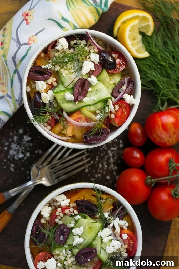 Bowls of Greek couscous with cucumber, olives and tomatoes.
