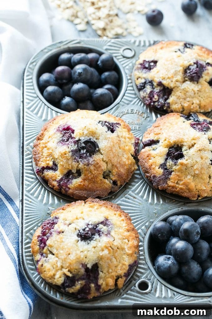 An overhead view of muffins in a tin with fresh blueberries.