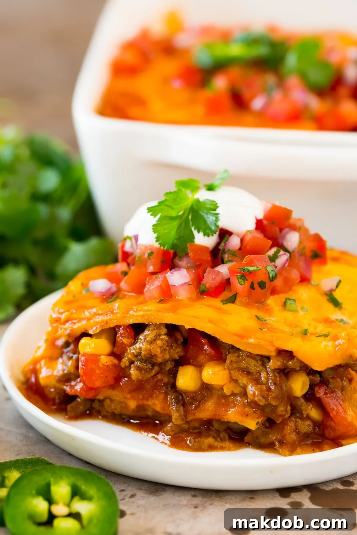 Zesty Mexican Layer Bake 2 A plate of Mexican casserole with visible layers of seasoned ground beef, soft tortillas, rich enchilada sauce, and melted cheddar cheese.