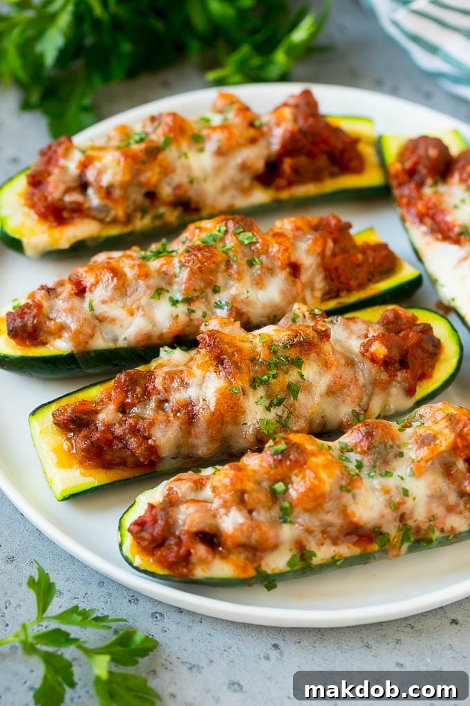 A plate of stuffed zucchini boats filled with a savory meat sauce and topped with mozzarella cheese, ready to be served.