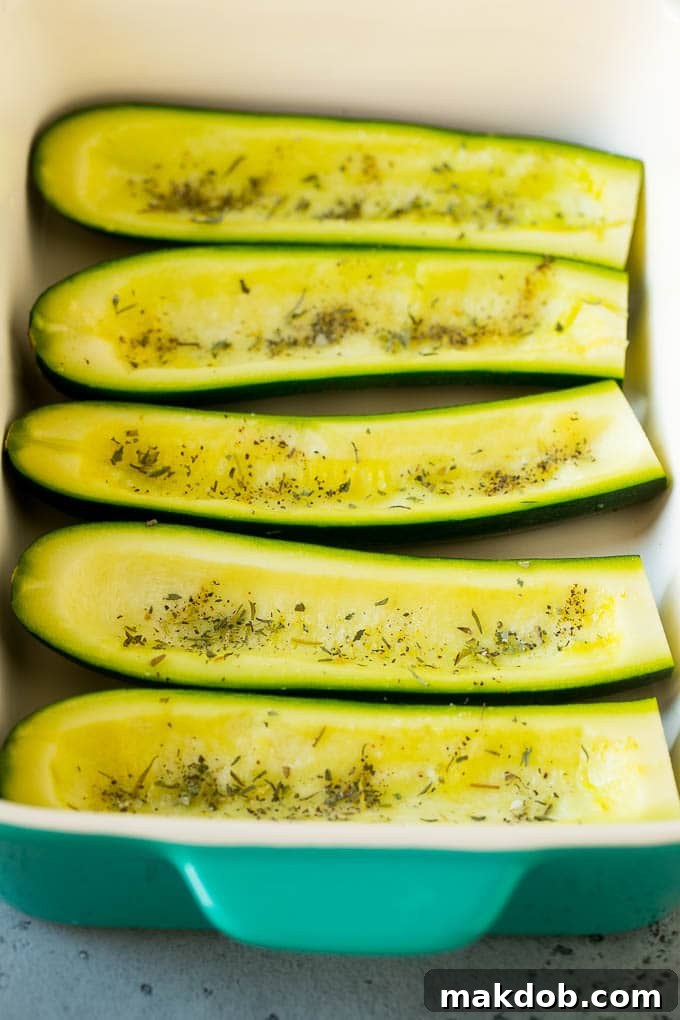 Hollowed out zucchini halves, seasoned and ready for filling, neatly arranged in a baking dish.