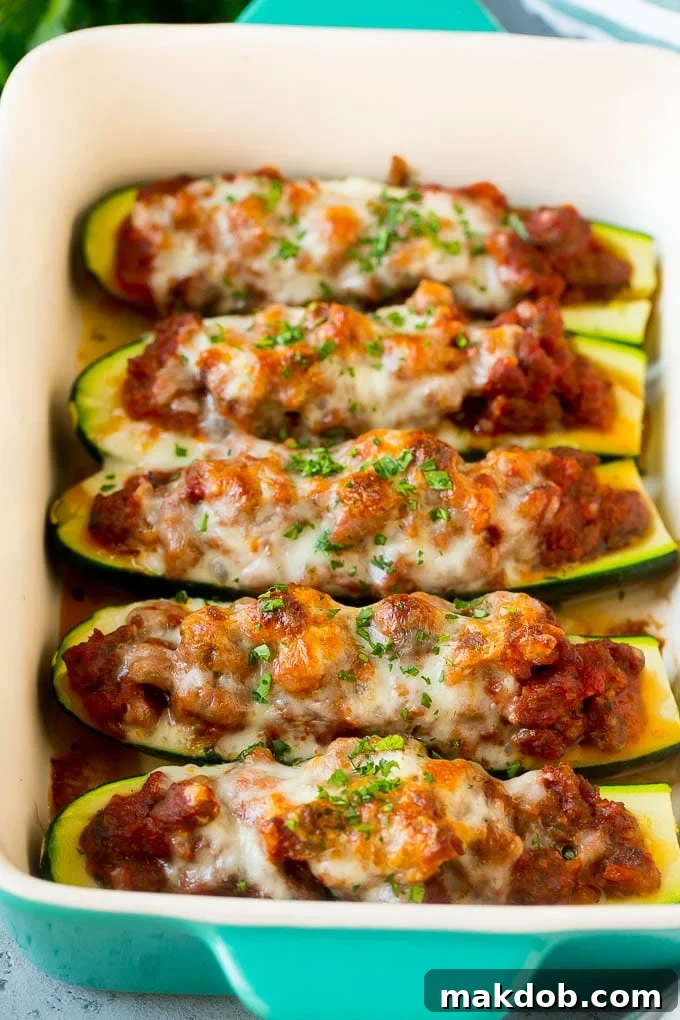 Stuffed zucchini boats overflowing with a rich meat sauce and topped with perfectly melted cheese, fresh out of the oven.