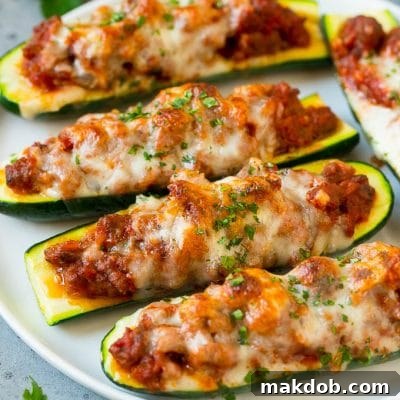 A plate of stuffed zucchini boats filled with a savory meat sauce and topped with mozzarella cheese.