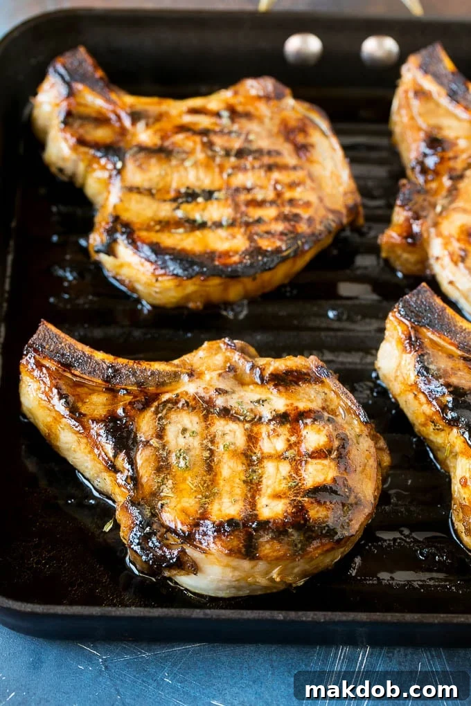 Beautifully marinated pork chops sizzling on a grill pan, showing perfect grill marks.