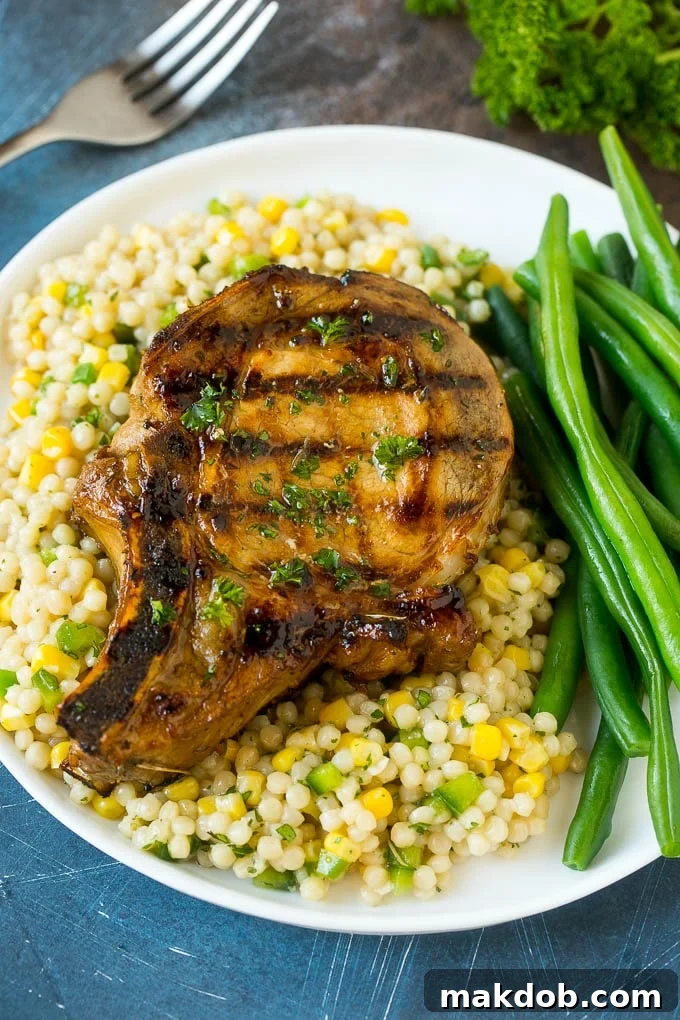 A delicious meal featuring grilled pork chops with the perfect marinade, served over couscous and accompanied by fresh green beans.