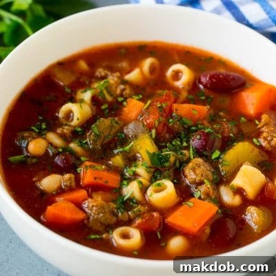 A bowl of pasta e fagioli soup with colorful veggies, ditalini pasta, two types of beans and ground beef.