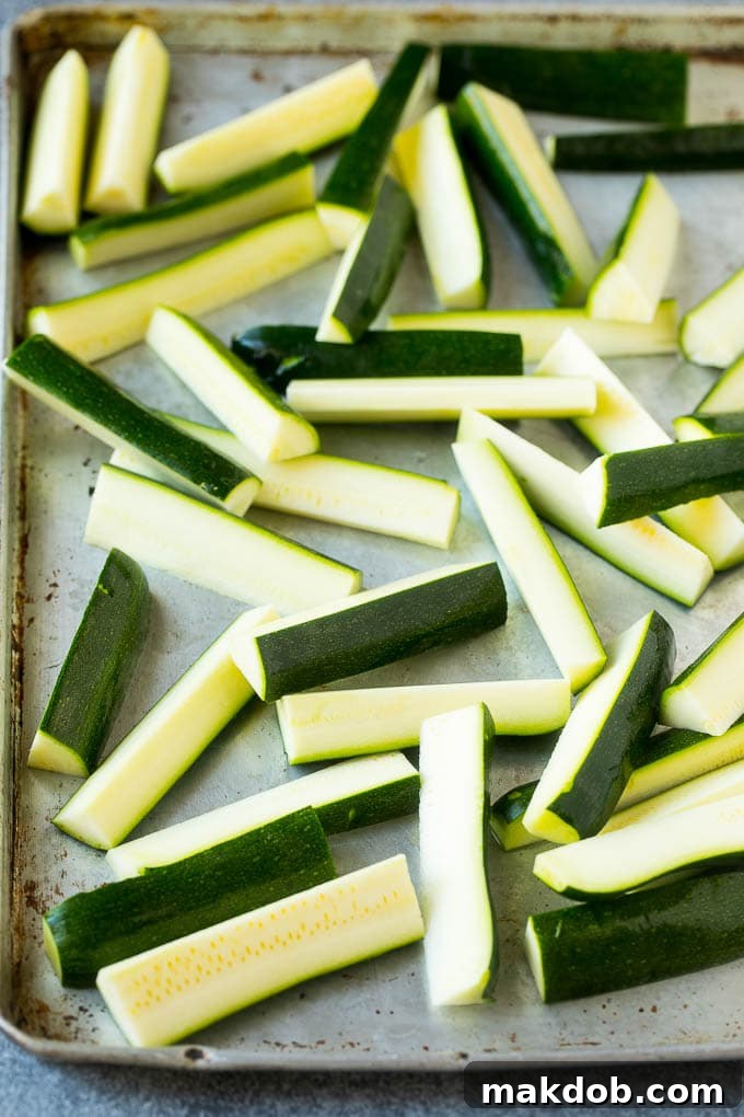 Raw zucchini sticks prepped on a sheet pan, ready for coating.