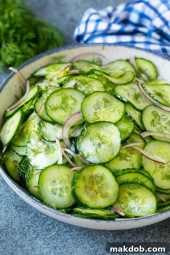 Crisp Cucumber Dill Salad Ready to Enjoy A close-up shot of a full bowl of crisp cucumber salad, vibrant with thinly sliced cucumbers, red onion, and generous amounts of chopped fresh dill, ready to be served.