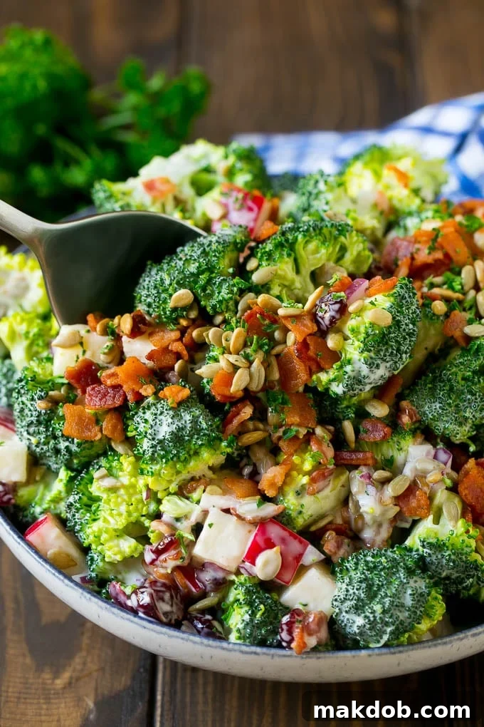 Broccoli Salad Recipe | Creamy Broccoli Salad | Bacon Broccoli Salad #salad #broccoli #bacon #apple #dinneratthezoo #sidedish A serving spoon in a bowl of bacon broccoli salad.