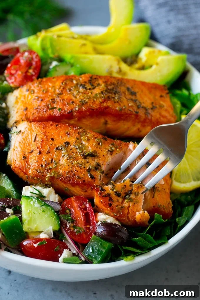 A fork cutting into a salmon fillet in Greek salmon salad.