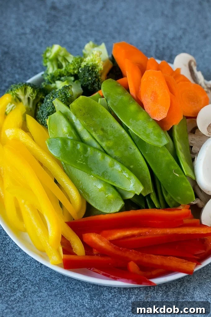 Vegetable Stir Fry Recipe | Veggie Stir Fry | Broccoli Stir Fry #vegetarian #vegetables #broccoli #dinner #dinneratthezoo A vibrant assortment of bell peppers, snow peas, carrots, mushrooms, and broccoli artfully arranged on a white plate, showcasing the fresh ingredients for a vegetable stir fry.