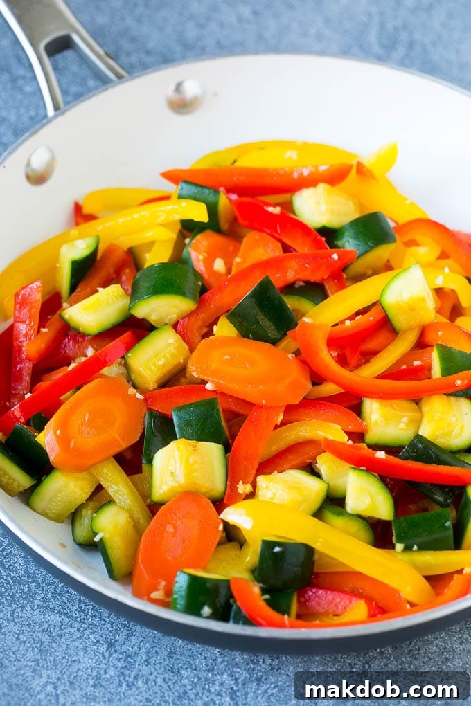 A pan of sauteed peppers, zucchini and carrots.