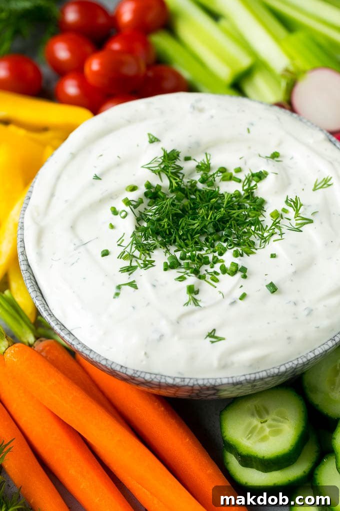 Garden Herb Dip 5 A beautifully arranged bowl of creamy, herb-infused veggie dip, nestled among an abundant and colorful spread of fresh, raw vegetables, including carrots, celery, bell peppers, broccoli, and cucumbers, inviting guests to indulge.