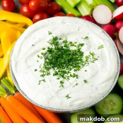 Veggie dip topped with fresh herbs and served with colorful vegetables.