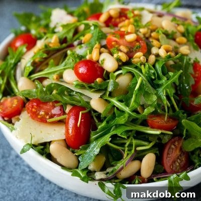 Arugula salad made with white beans, tomatoes, parmesan cheese and pine nuts.