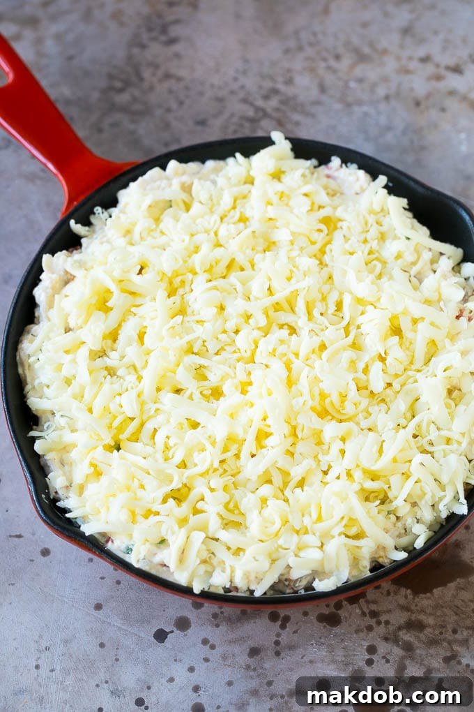 A skillet of creamy Reuben dip, freshly baked and topped with a generous layer of browned, melted shredded Swiss cheese, ready for serving.