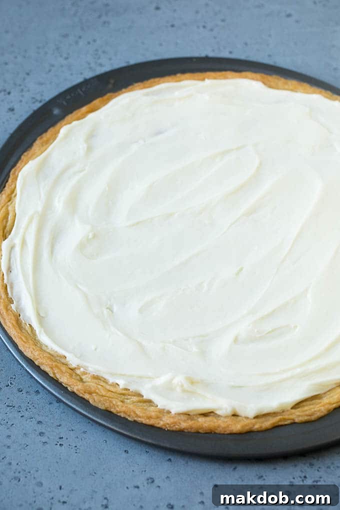 Cream Cheese Frosting for Fruit Pizza A sugar cookie crust topped with a generous layer of creamy cream cheese frosting, ready for fruit.