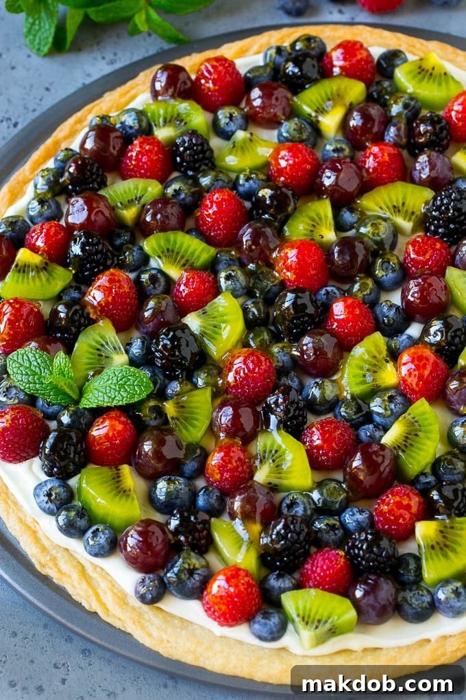 Colorful Fruit Pizza Topping Ideas A beautifully arranged fruit pizza, topped with vibrant berries, sliced kiwi, and green grapes.