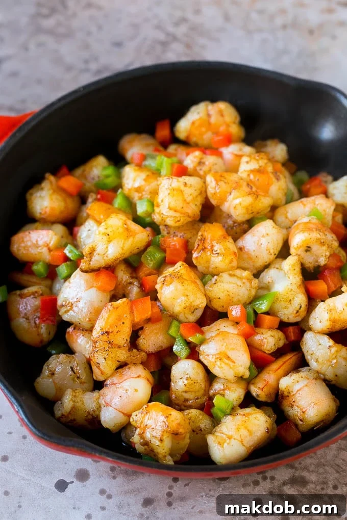 A skillet full of chopped shrimp and bell peppers.