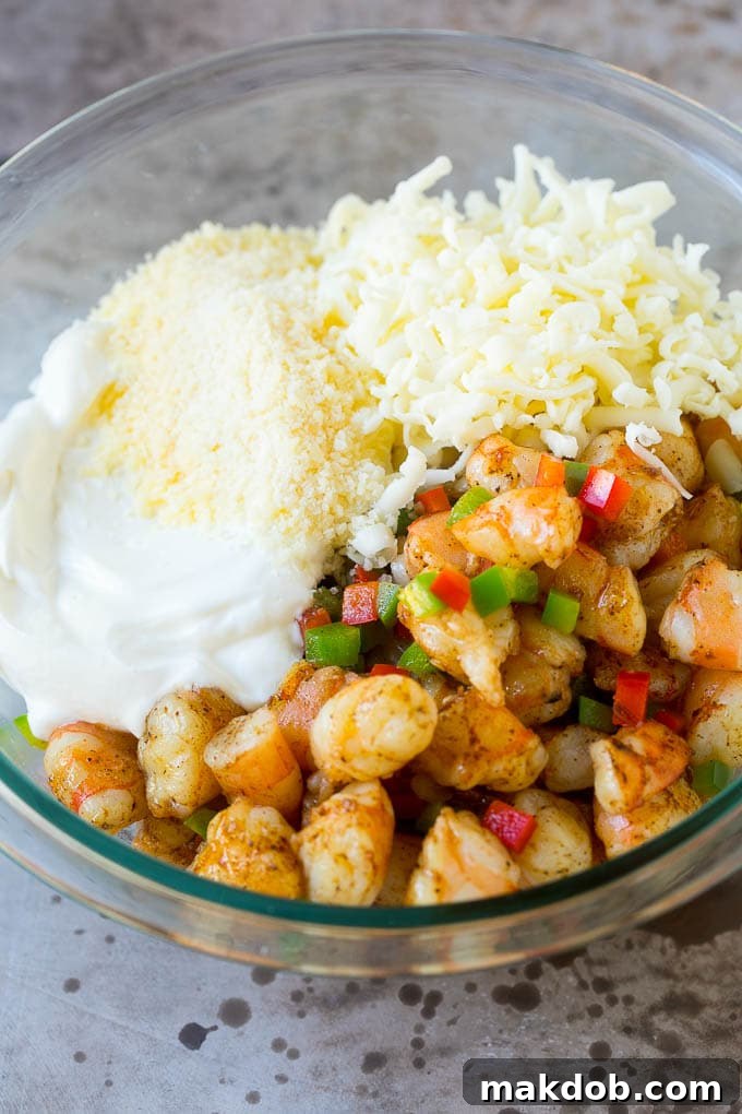 Chopped shrimp, peppers, cheese and sour cream in a bowl.