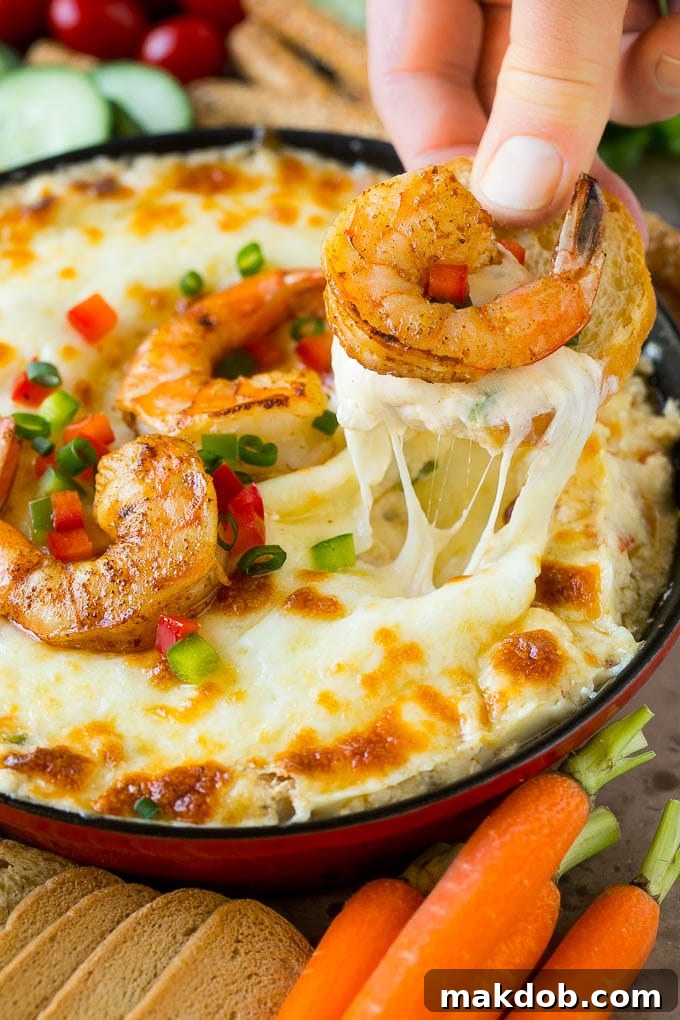 A hand scooping out a portion of shrimp dip with a piece of bread.