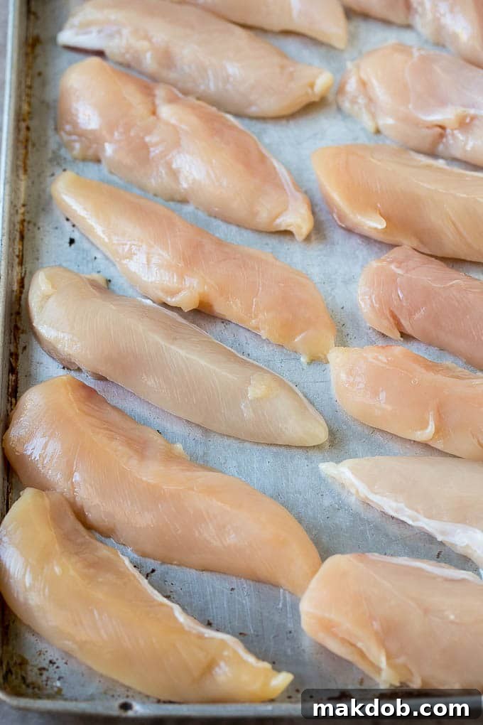 Raw chicken tenders on a sheet pan.