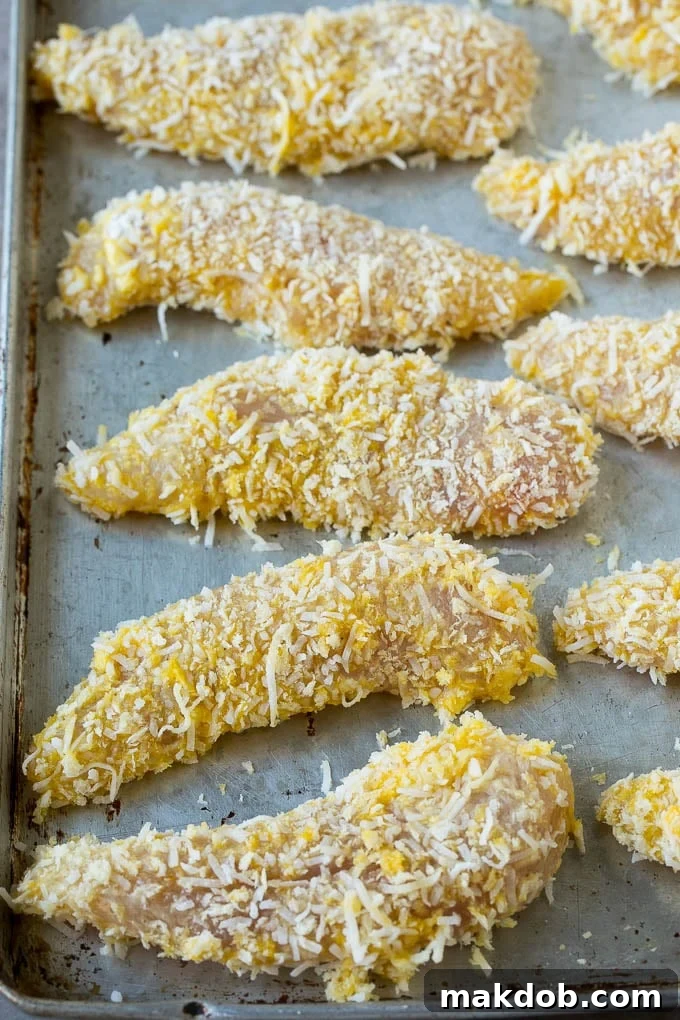 Chicken tenders coated in a coconut mixture on a sheet pan.