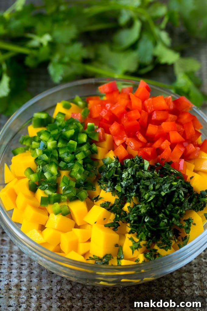 Diced mango, jalapeno, red pepper and cilantro in a bowl.