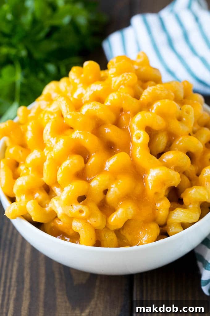 A close-up of a delicious serving of baked mac and cheese. A generous bowl of homemade baked macaroni and cheese, topped with fresh parsley.