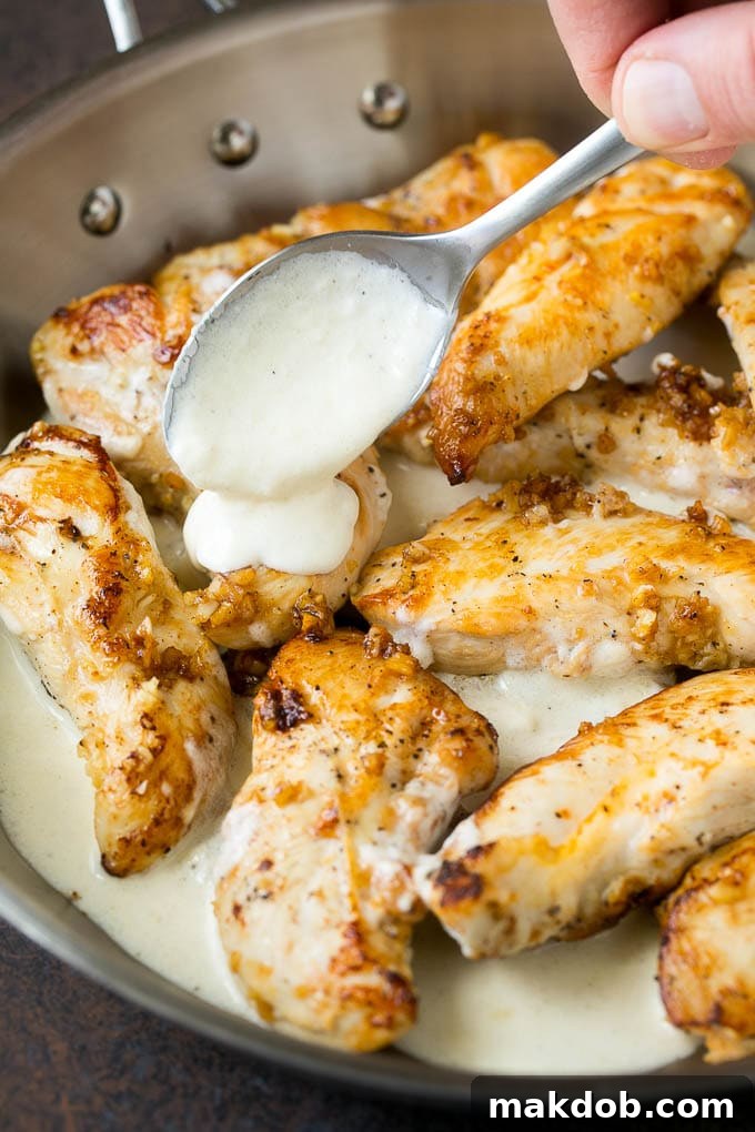 Creamy Garlic Chicken Recipe | Chicken Breast Tenders | Sauteed Chicken #chicken #garlic #parmesan #dinner #glutenfree #keto #lowcarb #dinneratthezoo A spoon pouring parmesan cream sauce over garlic chicken.