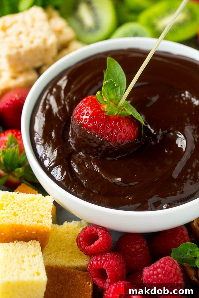 A strawberry on a skewer dipped into a bowl of chocolate fondue, highlighting its rich texture.