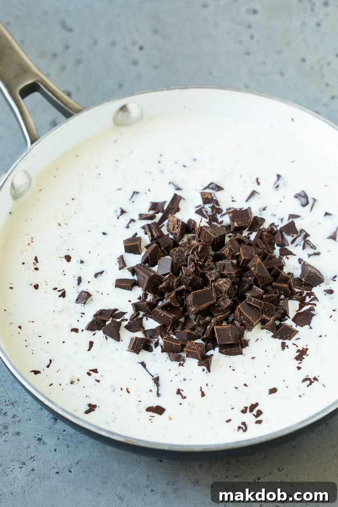Chopped semi-sweet chocolate chunks and heavy cream in a skillet, ready to be melted.