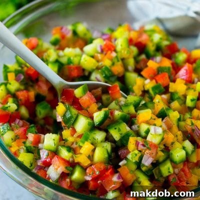 A bowl of Israeli salad with a serving spoon in it.