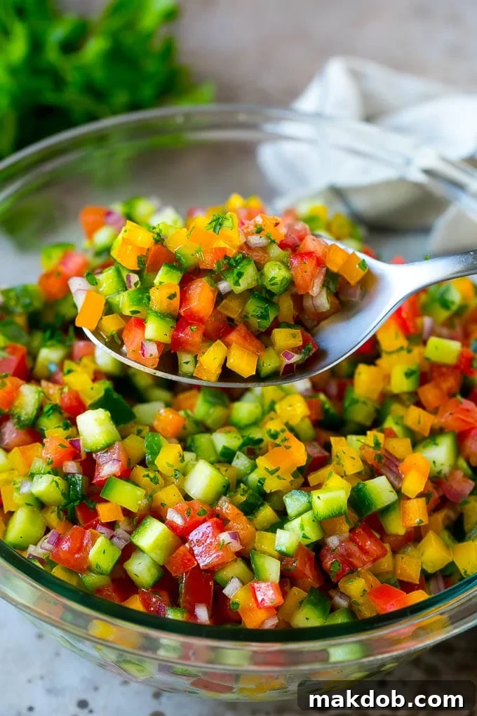 A spoon holding up a serving of Israeli salad.
