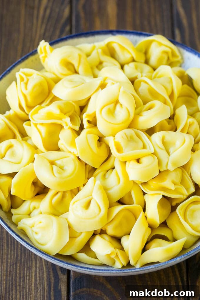 A close-up shot of perfectly cooked cheese tortellini, glistening and ready for assembly into a delicious salad.