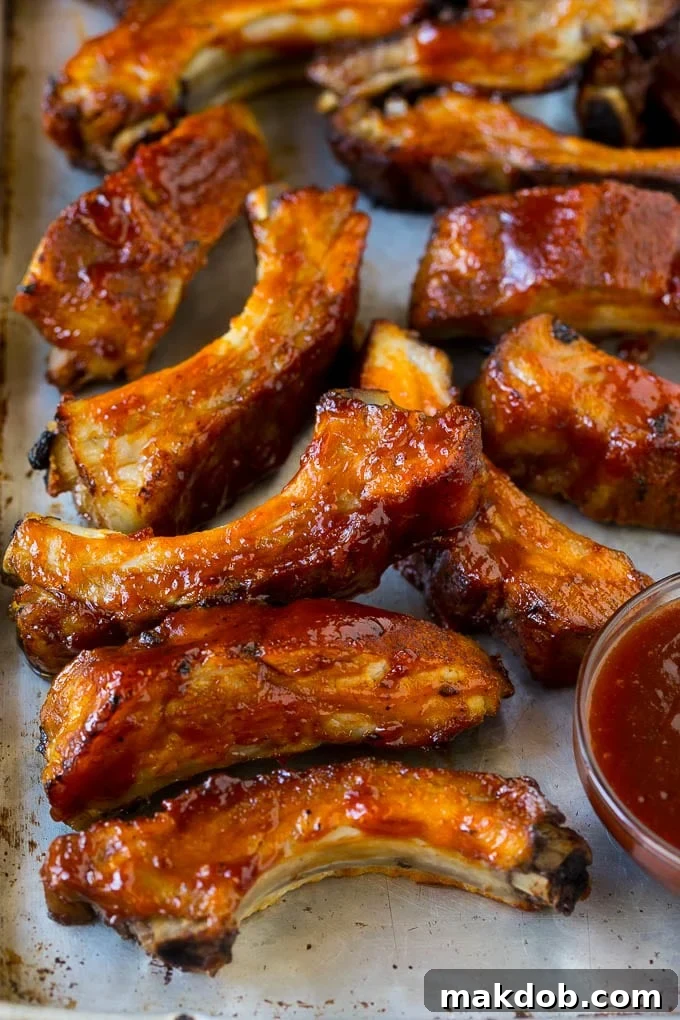 Slow cooker ribs coated in BBQ sauce on a sheet pan.