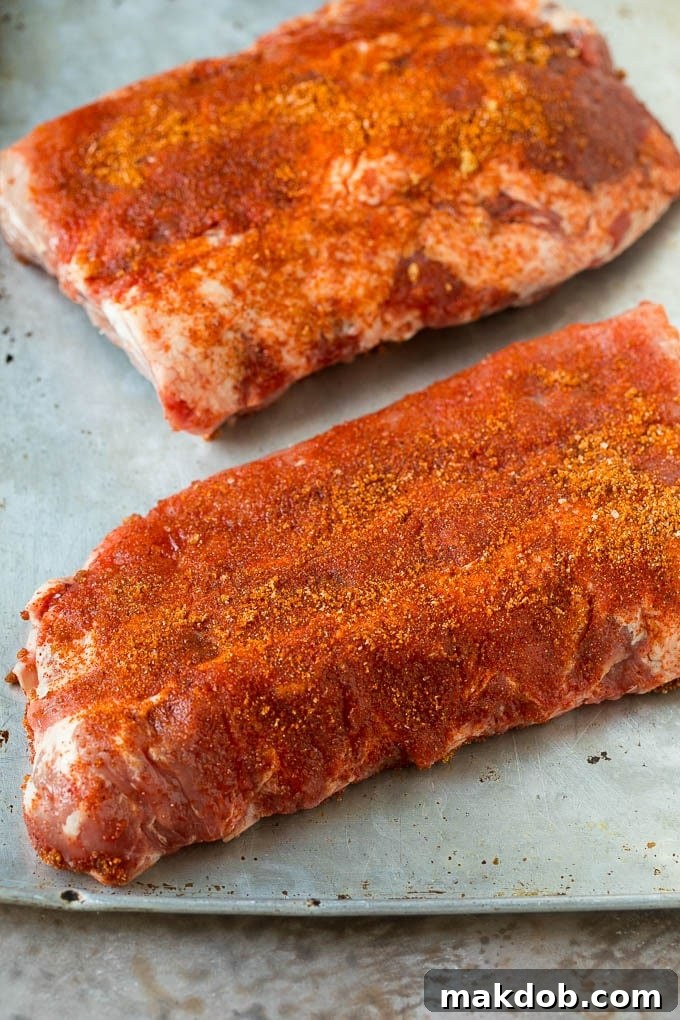 Slabs of uncooked ribs coated in BBQ spice rub.
