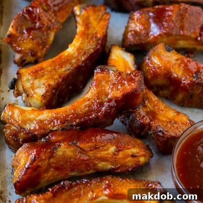 Slow cooker ribs coated in BBQ sauce on a sheet pan.