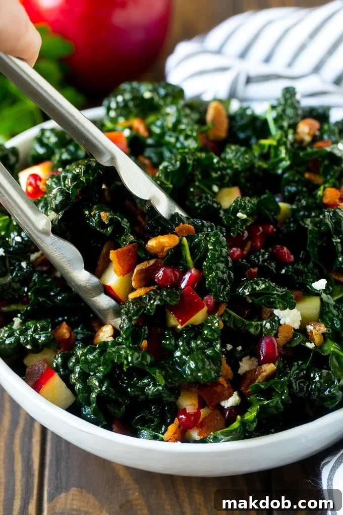Tongs in a bowl of kale and apple salad.