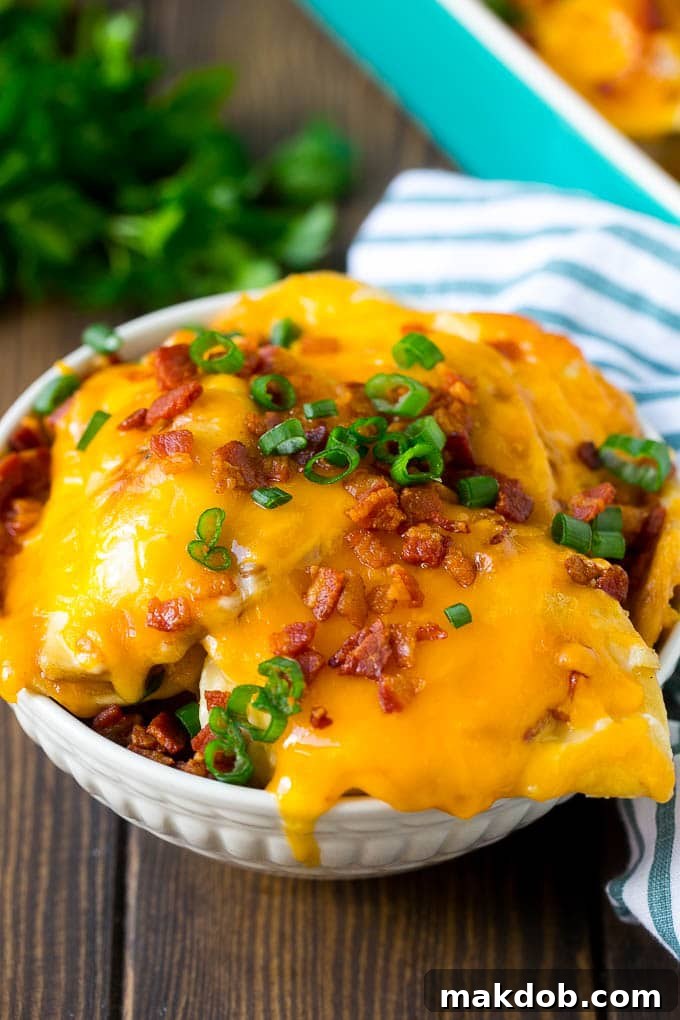 Pierogi Casserole Recipe | Potato Casserole #pierogis #casserole #bacon #cheddar #dinner #dinneratthezoo A bowl of pierogi casserole topped with cheddar cheese and bacon.