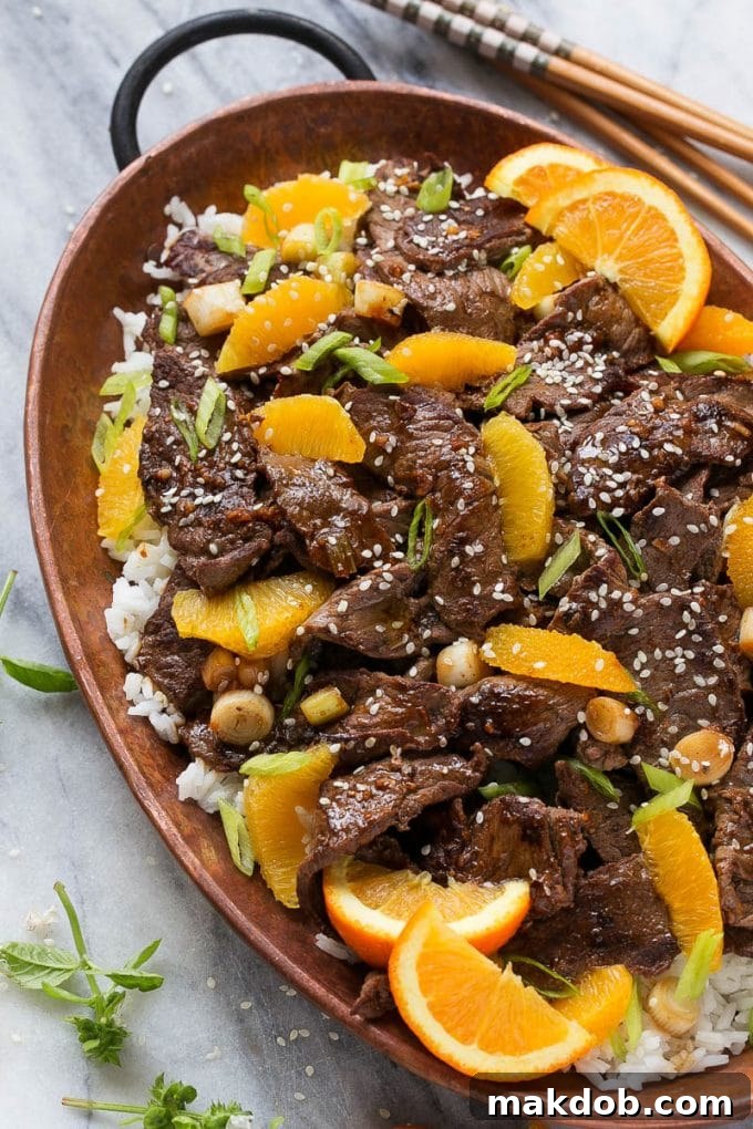 Homemade Orange Beef Stir Fry served over fluffy white rice, garnished with green onions and sesame seeds.