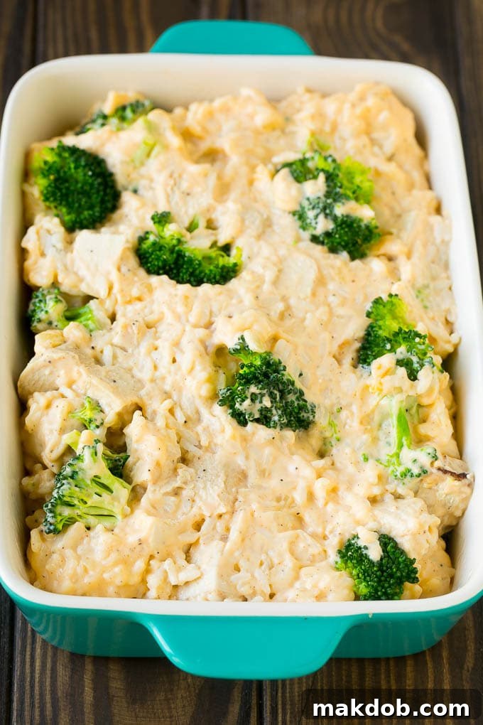 Creamy Chicken, Rice, and Broccoli Casserole Ready for the Oven A creamy, rich chicken and rice mixture, studded with green broccoli, nestled in a casserole dish before baking, topped with a hint of cheese.