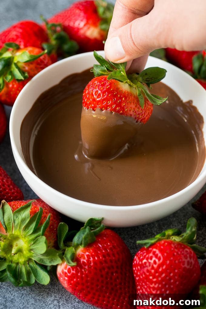 Chocolate Strawberry Indulgence 4 A strawberry being dipped into a bowl of melted chocolate.
